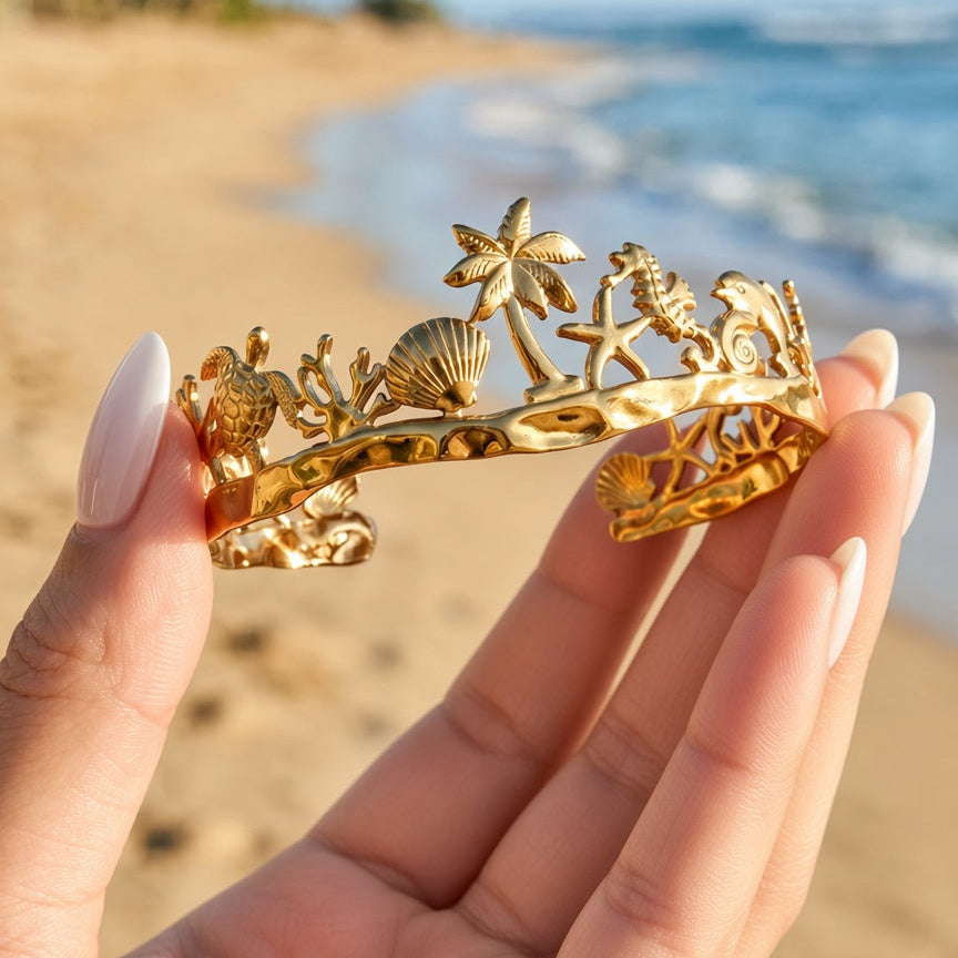 Buccoo Reef gold cuff held on the beach